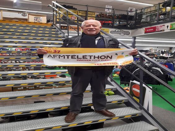 Le propriétaire du magasin Campana tient la banderole téléthon